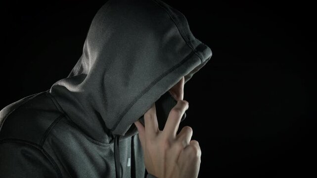 Male hacker breaking password. A hacker speaking on phone and is caught by police indoor. A concept of cyber crime in the modern life.