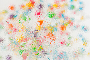 Colorful glass surface with water droplets forming soft artistic blur, refraction and texture. Concept of creative craft, color blending, fluid art inspiration, visual distortion and dreamy background