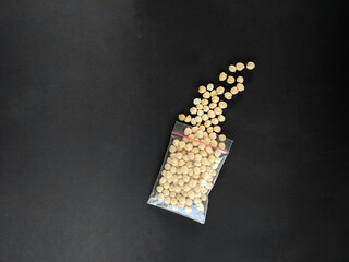 macadamia nuts shelled and packed in small plastic, bags on a black background
