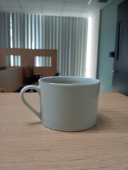 Striped Ceramic Mug with Coffee or Tea on a Gray Textured Floor