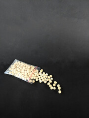 macadamia nuts shelled and packed in small plastic, bags on a black background
