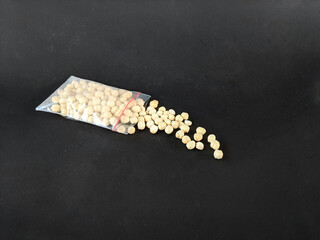 macadamia nuts shelled and packed in small plastic, bags on a black background
