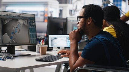 African american wheelchair user testing CAD software for manufacturing solar panels, factory...