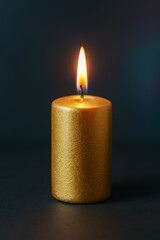 Beautiful golden candle with flame on dark background