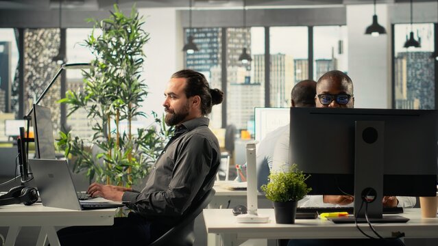 Professional coworkers and managers engaged in report sharing and data visualization. Multiethnic team uses forecasting, analytics, and documentation to strengthen business strategy.