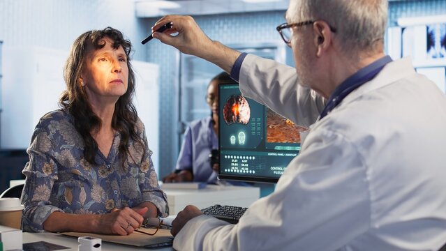Healthcare expert man conducting a concussion test with pen light in cabinet, evaluating the woman focus, coordination and pupil reaction after a suspected head trauma. Camera A.