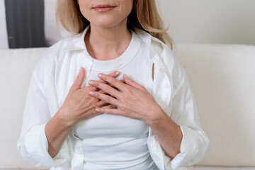 Calm mature woman practicing meditation for mental health and stress relief at home