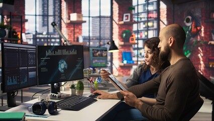 Startup workers team watching business conference on PC monitor, writing down info on notebook and sharing insights. Employees looking at presentation graphs on computer, taking notes. Camera A.