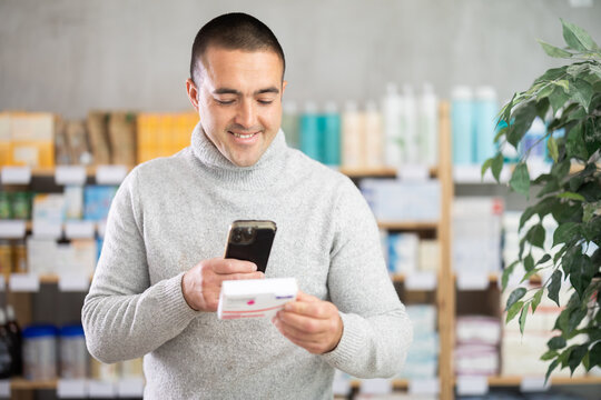 Young man buyer scanning qr code for box of paracetamol tablets in pharmacy