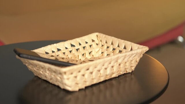 People putting phones and headphones in basket for digital detox. Close-up of several people putting their smartphones and a pair of headphones into a basket on a table, symbolizing a digital detox