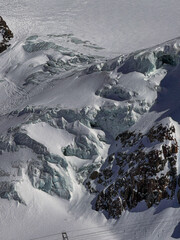 Snowy glacier landscape with dramatic rocky ridges in the Swiss Alps near Zermatt. Winter mountain scenery captured in bright sunlight