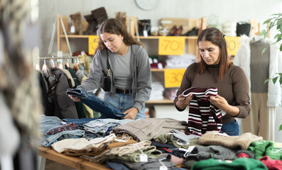 During November sales, Latin woman choose and buy buy something autumn clothes. Discount season, promotional offers. Chain store of affordable clothing. Buyer browsing clothes goods in background