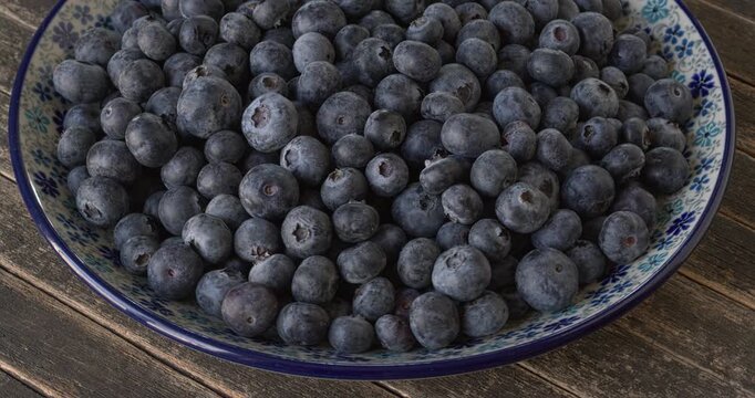 Fresh northern highbush blueberry berries on a handcolored plate. Table spin. 