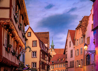 Christmas decorations on half timbered houses in Colmar, France glow at sunset