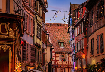 Obraz premium Christmas decorations on half timbered houses in Colmar, France glow at sunset