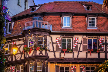 Christmas decorations on half timbered houses in Colmar, France glow at sunset