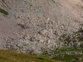 Epic alpine mountains landscape of the Mangart massive rugged cliffs with atmospheric light from the cloudy sky 