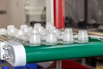 Production line for the production of plastic packaging by injection molding. Small round disposable containers on a conveyor, automation and modern production technologies