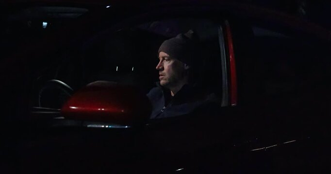 Man sitting in car after being pulled over by police, scrambling to put on seat belt before the officer arrives at his window