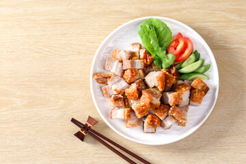 Crispy pork belly on white plate and dipping sauce on the wooden table