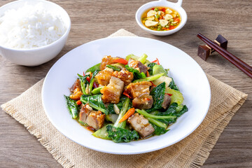 Stir fried kale with crispy pork in oyster sauce on white plate