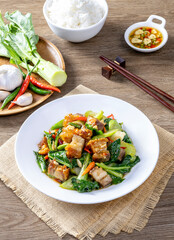 Stir fried kale with crispy pork in oyster sauce on white plate