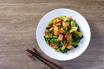 Stir fried kale with crispy pork in oyster sauce on white plate