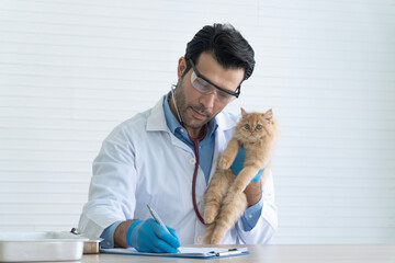 Professional male veterinarian with safety glasses holding ginger Persian kitten and writing medical prescription on clipboard. Doctor recording health checkup results in animal clinic.