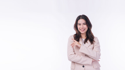 Happy young business woman pointing finger at copy space while looking at camera. Smiling professional lady in beige suit showing empty space for text isolated on white background.