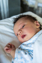 Newborn baby boy looking while resting in crib