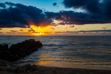 Dramatic Ocean Sunrise with Golden Light and Dark Storm Clouds Over the Water