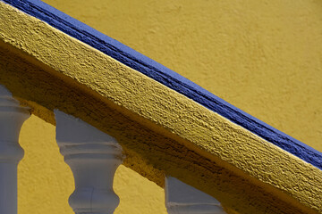 Closeup of white and blue balustrade against yellow wall