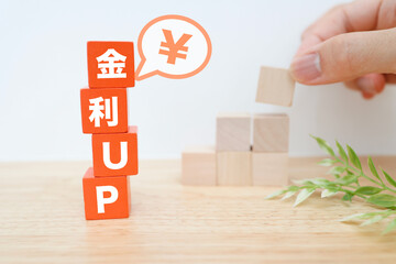 金利上昇と円の価値を示す積み木と吹き出しの金融イメージ。