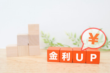 金利上昇と円の価値を示す積み木と吹き出しの金融イメージ。