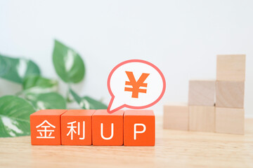 金利上昇と円の価値を示す積み木と吹き出しの金融イメージ。