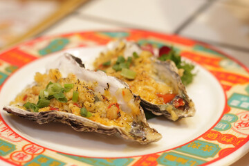 Oysters topped with toppings served on a plate in a restaurant