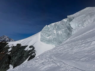 Steep alpine glacier wall and rugged snowy ridge near Zermatt, Switzerland. Crisp winter light highlights the icy textures and dramatic mountain landscape in the Swiss Alps.