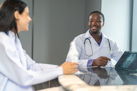 Diverse medical team african male doctor and female doctor collaborating and reviewing medical documents writing and discussing patient data in hospital office, teamwork in healthcare, patient care