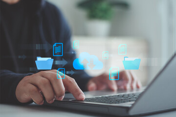 Cloud computing technology concept. Businessman using laptop with data transfer between folder and cloud storage, business digital file management, represented by blue arrow and document icon.