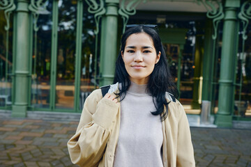 Obraz premium Woman outdoors in casual clothing near green architectural columns in daytime urban setting, calm expression, street style and confident vibe, approachable appearance