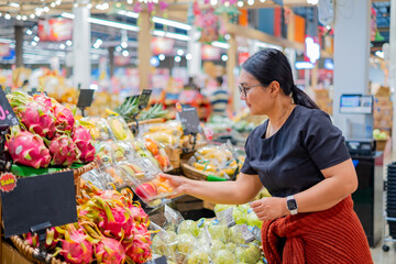 A woman shopping for fresh vegetables at a supermarket, carefully selecting produce and placing items into her cart, representing healthy living, grocery shopping, and everyday lifestyle choices.