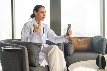 Female doctor using smartphone for remote work, conducting video call consultation to provide health advice and telemedicine services for patient, online medical care, diagnosis and treatment