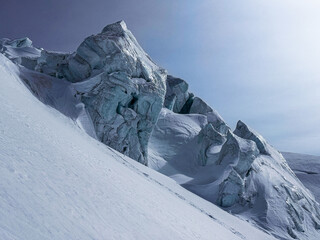 Dramatic ice formations and rugged glacier textures on a steep alpine slope under clear winter skies.A striking natural landscape showcasing shapes carved by snow, wind, and cold.