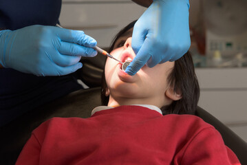 Child at the dental office. Children dental health. Dentist examining child's teeth in regular dentistry check up. Pediatric dentist examining his patient mouth with dental mirror in dental clinic.