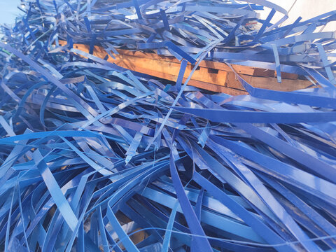 A chaotic mass of blue synthetic strapping spread across a wooden pallet, showcasing industrial packaging material in a highly detailed close-up scene