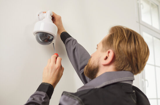 CCTV wall installation connecting dome camera, worker setting up system for viewing and recording, motion detection home security, smart AI technology, night vision, mounting powering up and testing