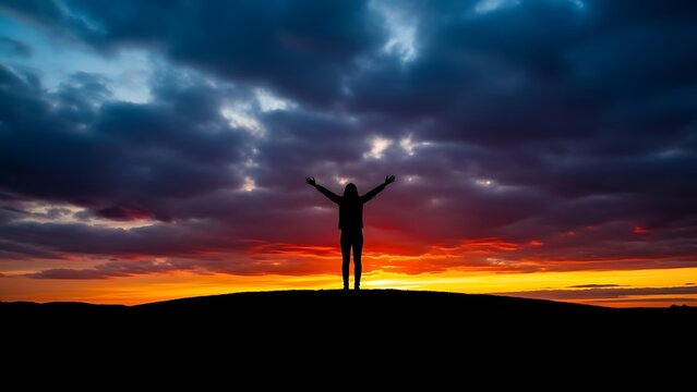 Silhouette of a person with arms outstretched against a dramatic sunset sky symbolizing hope and achievement