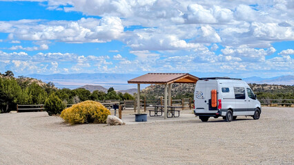 RV camper van parked at campsite with covered picnic tables and mountain vista views