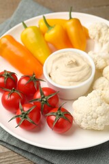 Different fresh vegetables and sauce on wooden table, closeup