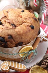 Tasty Christmas panettone cake decorated with cinnamon stick and dry orange slice on table, closeup